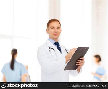 medicine, profession, teamwork and healthcare concept - smiling male doctor with clipboard and stethoscope writing prescription over group of medics