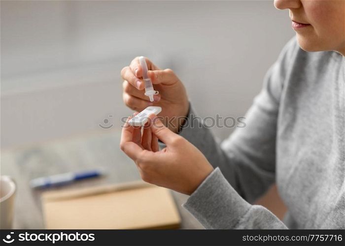 medicine, quarantine and pandemic concept - close up of woman making self testing coronavirus test at home. woman making self testing coronavirus test at home