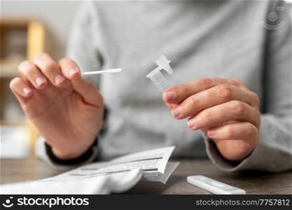 medicine, quarantine and pandemic concept - hands of woman making self testing coronavirus test and stirring swab in reagent at home. woman making self testing coronavirus test at home