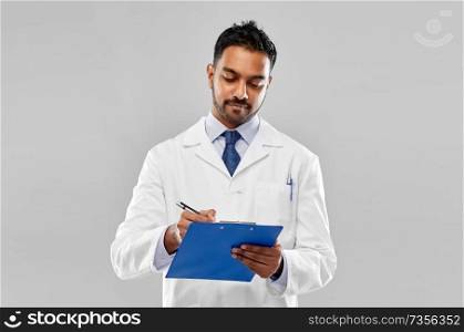 medicine, science and profession concept - indian male doctor or scientist in white coat with clipboard over grey background. indian male doctor or scientist with clipboard