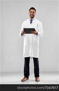 medicine, science and profession concept - smiling indian male doctor or scientist in white coat with tablet computer over grey background. indian doctor or scientist with tablet computer