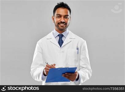 medicine, science and profession concept - smiling indian male doctor or scientist in white coat with clipboard over grey background. smiling indian doctor or scientist with clipboard