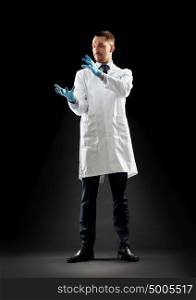 medicine, science, healthcare and people concept - doctor or scientist in white coat and medical gloves touching something invisible over black background. doctor or scientist in lab coat and medical gloves