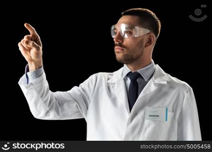 medicine, science, healthcare and people concept - male doctor or scientist in white coat and safety glasses touching something invisible over black background. doctor or scientist in lab coat and safety glasses