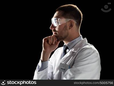 medicine, science, healthcare and people concept - male doctor or scientist in white coat and safety glasses over black background. doctor or scientist in lab coat and safety glasses