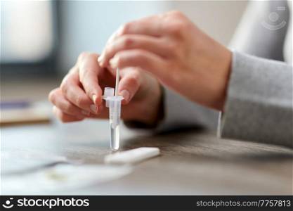 medicine, self testing and pandemic concept - hands of woman making coronavirus test and stirring swab in reagent at home. woman making self testing coronavirus test at home