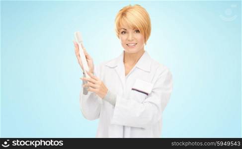 medicine, stomatology, people and dental hygiene concept - smiling female doctor with big toothbrush over blue background