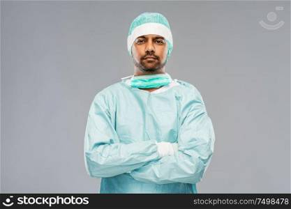 medicine, surgery and people concept - indian male doctor or surgeon in protective wear over grey background. indian male doctor or surgeon in protective wear