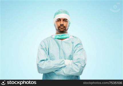medicine, surgery and people concept - indian male doctor or surgeon in protective wear over blue background. indian male doctor or surgeon in protective wear