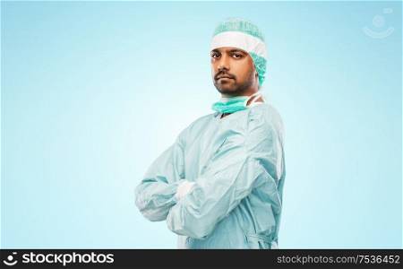 medicine, surgery and people concept - indian male doctor or surgeon in protective wear over blue background. indian male doctor or surgeon in protective wear
