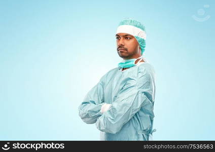 medicine, surgery and people concept - indian male doctor or surgeon in protective wear over blue background. indian male doctor or surgeon in protective wear