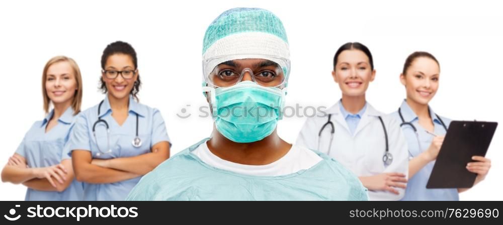medicine, surgery and people concept - indian male doctor or surgeon in mask, goggles and protective wear over smiling healthcare workers team on white background. indian doctor or surgeon and healthcare workers