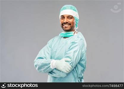 medicine, surgery and people concept - smiling indian male doctor or surgeon in protective wear over grey background. indian male doctor or surgeon in protective wear