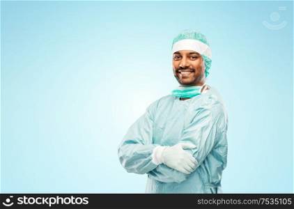 medicine, surgery and people concept - smiling indian male doctor or surgeon in protective wear over blue background. indian male doctor or surgeon in protective wear