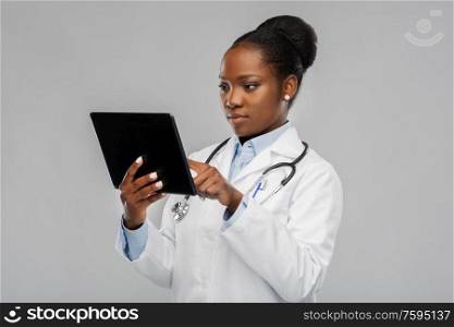 medicine, technology and healthcare concept - african american female doctor or in white coat with tablet pc computer and stethoscope over background. african american female doctor with tablet pc