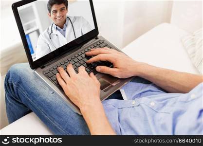 medicine, technology and healthcare concept - close up of man or patient having video chat with doctor on laptop computer at home. patient having video chat with doctor on laptop