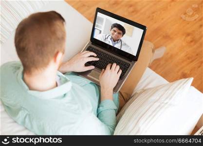 medicine, technology and healthcare concept - close up of man or patient having video call with male doctor on laptop computer at home. patient having video call with doctor on laptop