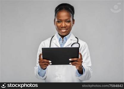 medicine, technology and healthcare concept - happy smiling african american female doctor or in white coat with tablet pc computer and stethoscope over background. african american female doctor with tablet pc