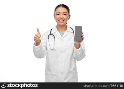 medicine, technology and healthcare concept - happy smiling asian female doctor or nurse with stethoscope and smartphone showing thumbs up over white background. asian doctor with smartphone showing thumbs up