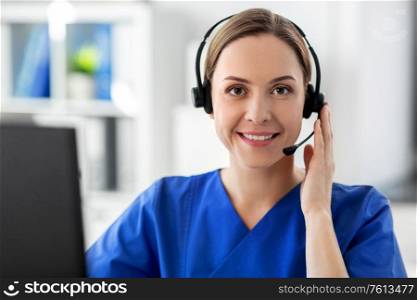 medicine, technology and healthcare concept - happy smiling female doctor or nurse with headset and computer working at hospital. doctor with headset and computer at hospital