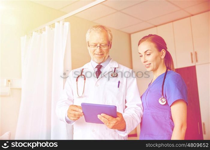 medicine, technology, health care and people concept - senior doctor and young nurse with tablet pc computer at hospital hospital ward