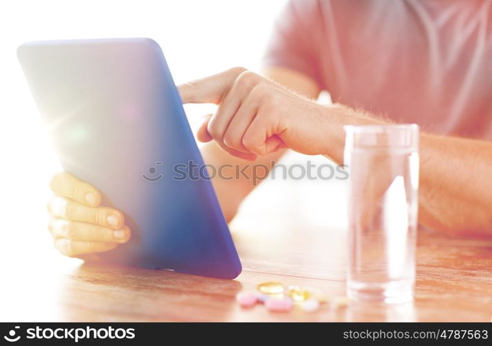 medicine, technology, nutritional supplements and people concept - close up of male hands with tablet pc computer, pills and water on table