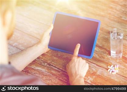 medicine, technology, nutritional supplements and people concept - close up of male hands pointing finger to blank tablet pc computer screen , pills and water on table