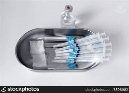 medicine, vaccination and healthcare concept - close up of disposable syringes, sterile wipes and jar with drug on table at hospital. close up of syringes, sterile wipes and medicine