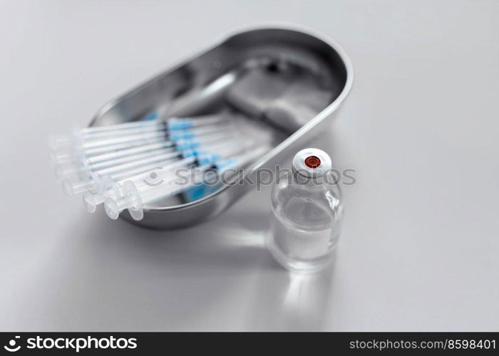 medicine, vaccination and healthcare concept - close up of disposable syringes, sterile wipes and jar with drug on table at hospital. close up of syringes, sterile wipes and medicine