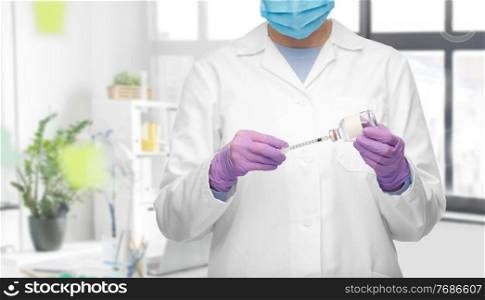 medicine, vaccination and healthcare concept - close up of female doctor or nurse in mask with drug and syringe over medical office at hospital on background. close up of doctor in mask with drug and syringe