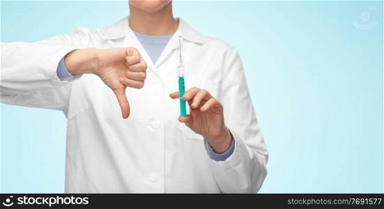 medicine, vaccination and healthcare concept - close up of female doctor or nurse with syringe showing thumbs down over blue background. close up of doctor with syringe shows thumbs down