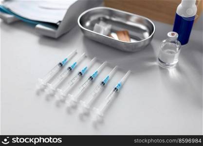 medicine, vaccination and healthcare concept - disposable syringes and other stuff on table at hospital. disposable syringes on table at hospital