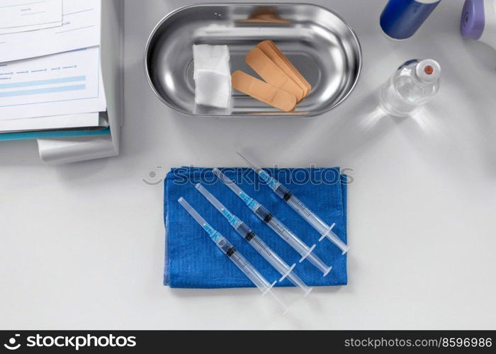 medicine, vaccination and healthcare concept - disposable syringes on blue wipe and other stuff on table at hospital. disposable syringes on blue wipe on table