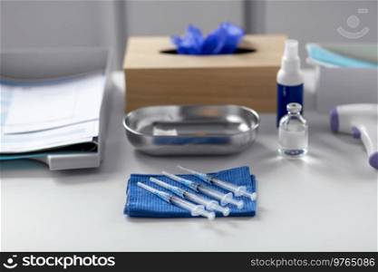 medicine, vaccination and healthcare concept - disposable syringes on blue wipe and other stuff on table at hospital. disposable syringes on blue wipe on table