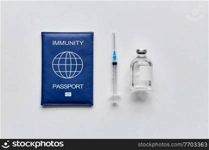 medicine, vaccination and healthcare concept - immunity passport, syringe and bottle with vaccine on white table. immunity passport, syringe and vaccine on table