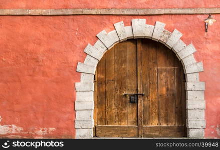 Medieval architecture background with a massive wooden door and an orange-pink aged wall, with copy space on left