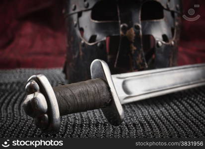 Medieval armour, helmet and sword, red canvas background