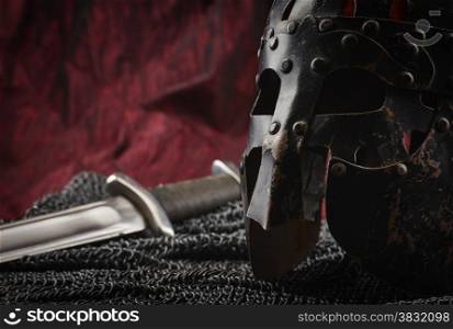 Medieval armour, helmet and sword, red canvas background