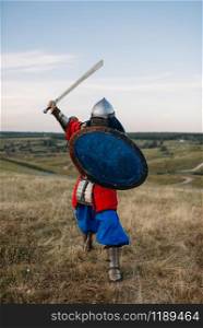 Medieval knight with sword poses in armour, great fighter. Armored ancient warriors in armor posing in the field. Medieval knight with sword poses in armor, fighter