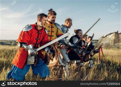 Medieval knights in armor and helmets standing in a row before battle. Armored ancient warrior in armour posing in the field
