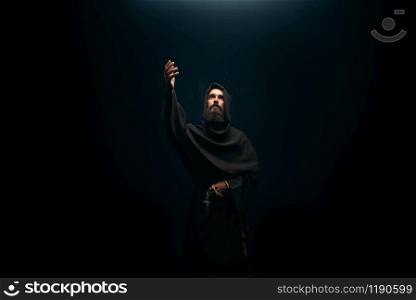 Medieval monk kneeling and praying, religion. Mysterious friar in dark cape, Mystery and spirituality. Medieval monk kneeling and praying, religion