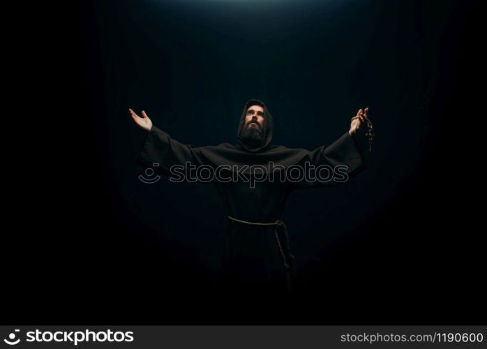 Medieval monk praying to the holy god, religion. Mysterious friar in dark cape, Mystery and spirituality