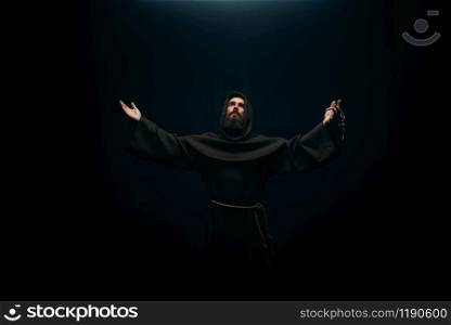 Medieval monk praying to the holy god, religion. Mysterious friar in dark cape, Mystery and spirituality