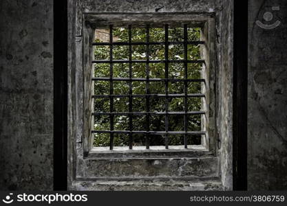 Medieval window with iron grating in Prague. Ancient stone walls, wooden frame and trees views