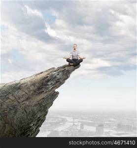 Meditating businesswoman. Young businesswoman sitting lotus pose on edge of rock mountain