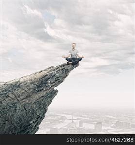 Meditating businesswoman. Young businesswoman sitting lotus pose on edge of rock mountain