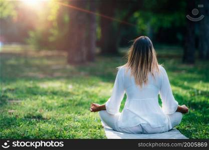 Meditating by the water, young woman in white, green nature background. Meditating by the Water, Green Nature Background