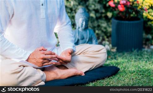 Meditating man. Peaceful man sitting in a lotus position and meditating in the garden.. Peaceful Man Meditating, Sitting in Lotus Position.