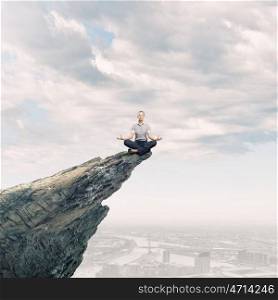 Meditating woman. Businesswoman in lotus pose on top of rock