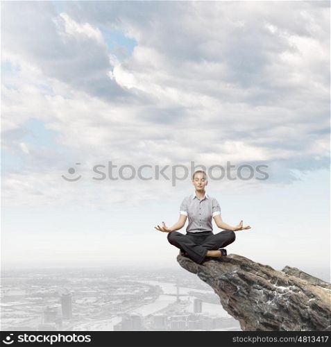 Meditating woman. Businesswoman in lotus pose on top of rock